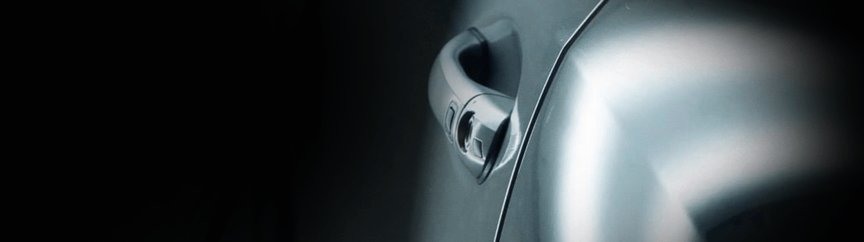 Close-up of a car door handle on a dark background.