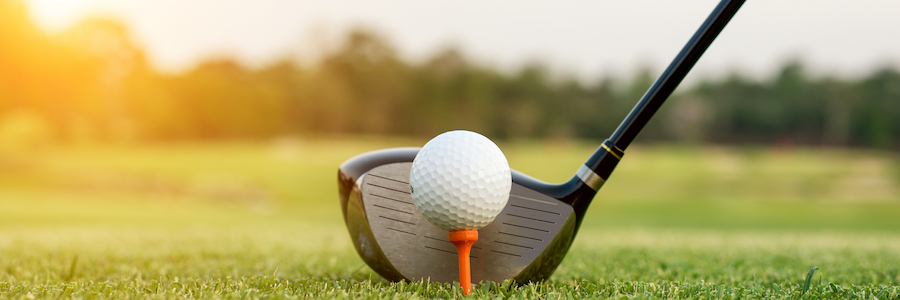 Golf club and ball in grass with sunlight. Close up at golf club and golf ball.