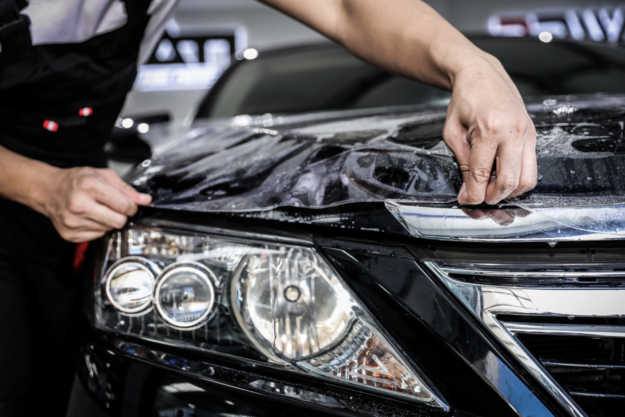 Person applying protective film to a car headlight.