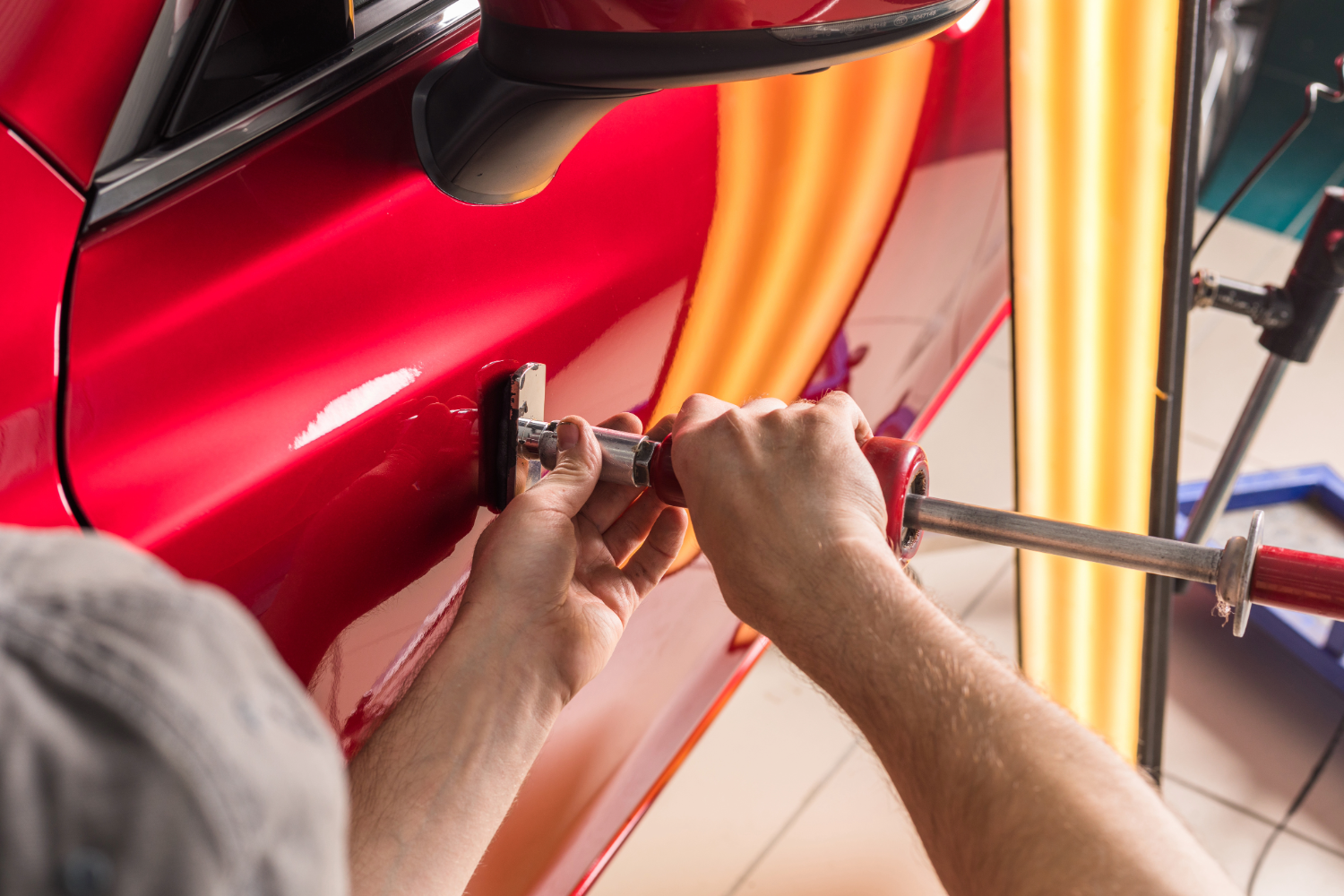 Removal of dents from red sedan without painting. PDR technology for car body repair.
