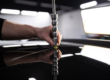 Employee of the car detailing studio removes minor dents from the roof of the car. Closeup on his hands and the tool.